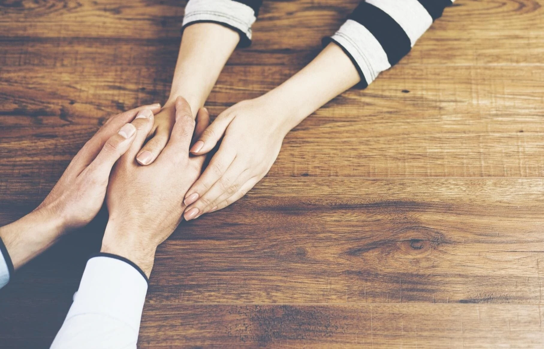 A boy and a girl holding hands on table. A boy and a girl holding hands on table.